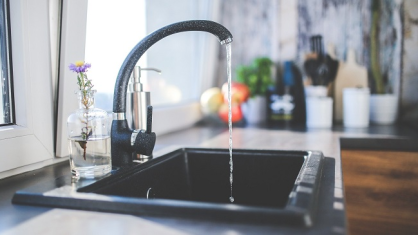 The image is an illustration showing water flowing from a kitchen faucet.